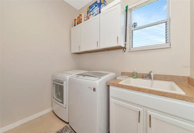 laundry room featuring cabinets, light tile patterned flooring, washer and dryer, and sink