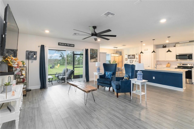 living room featuring sink, light wood-type flooring, and ceiling fan