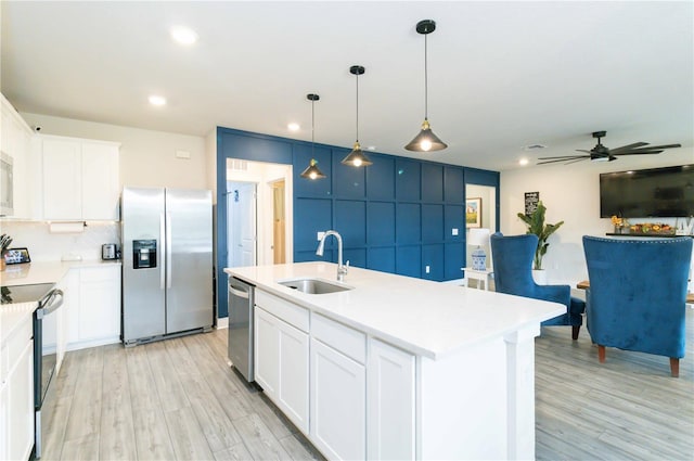 kitchen with appliances with stainless steel finishes, white cabinets, sink, and a center island with sink