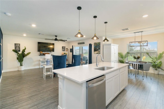 kitchen featuring dishwasher, sink, white cabinetry, light hardwood / wood-style flooring, and a kitchen island with sink