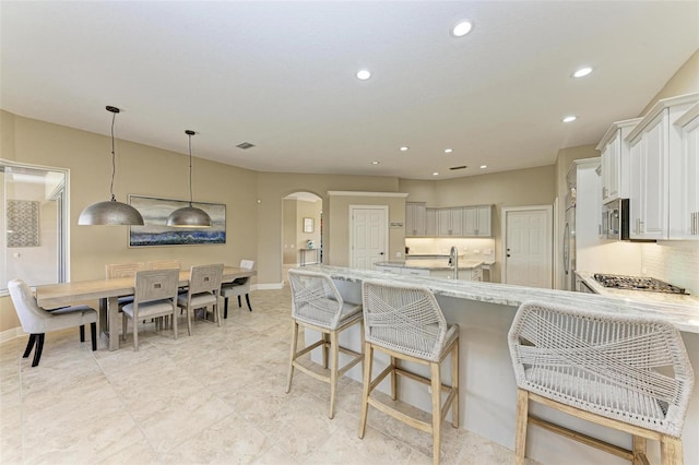 kitchen featuring light stone countertops, appliances with stainless steel finishes, tasteful backsplash, pendant lighting, and white cabinetry