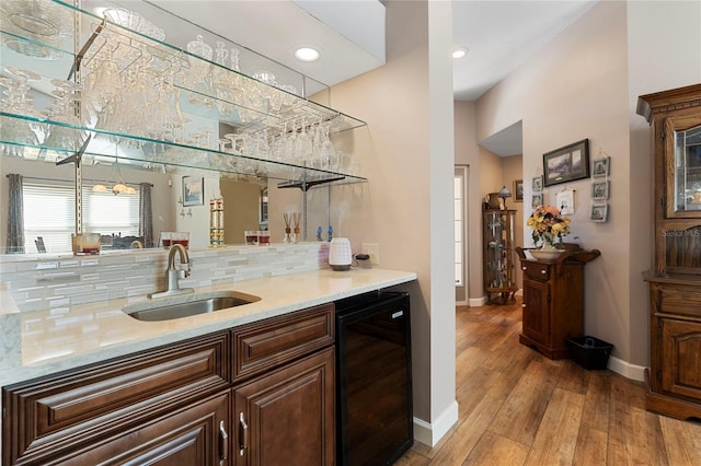 bar featuring wine cooler, backsplash, sink, and light hardwood / wood-style floors