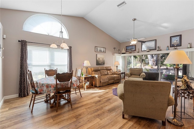 living room featuring light hardwood / wood-style flooring, high vaulted ceiling, and ceiling fan with notable chandelier