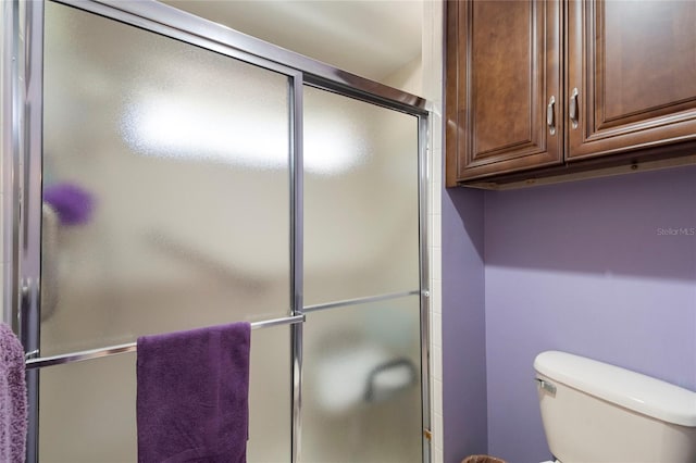 bathroom featuring toilet and a shower with door