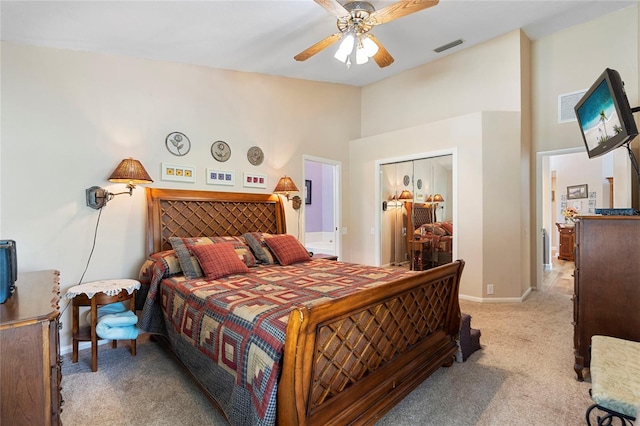 bedroom featuring a high ceiling, light carpet, a closet, and ceiling fan