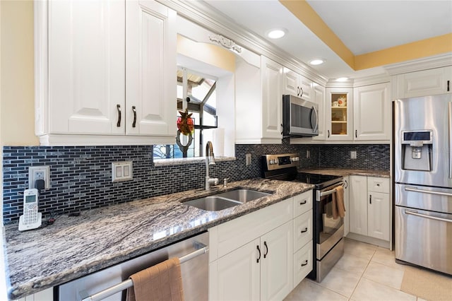 kitchen featuring sink, appliances with stainless steel finishes, white cabinetry, and dark stone counters