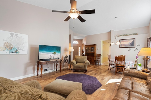 living room featuring light hardwood / wood-style flooring, high vaulted ceiling, and ceiling fan with notable chandelier