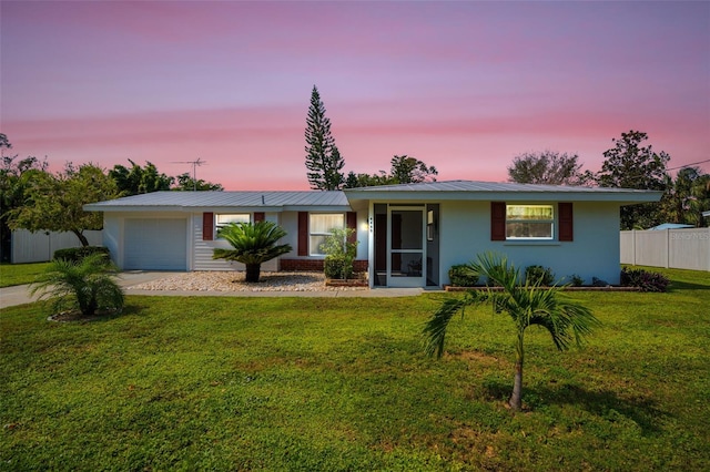 single story home featuring a garage and a lawn