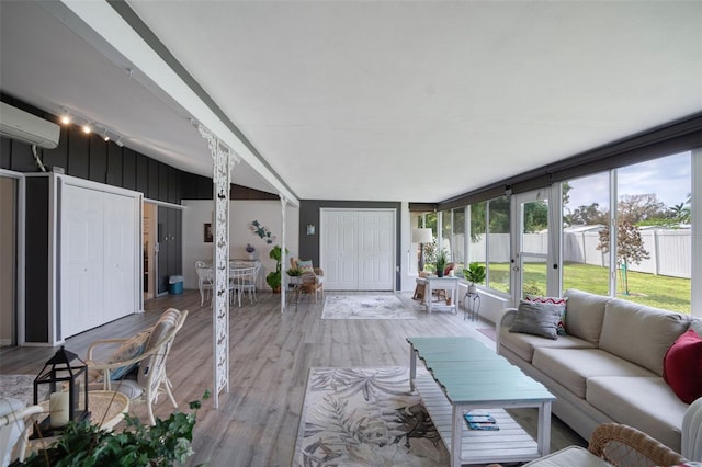 sunroom with lofted ceiling and a wall mounted air conditioner