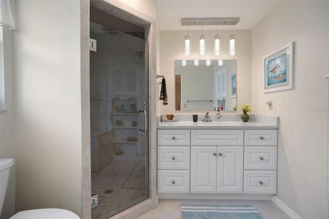 bathroom with a shower with door, vanity, toilet, and tile patterned floors