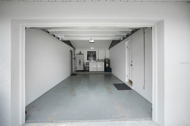 garage with electric water heater, separate washer and dryer, and white refrigerator