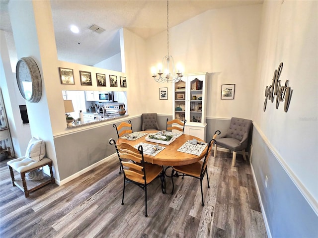 dining area featuring an inviting chandelier, hardwood / wood-style floors, and high vaulted ceiling