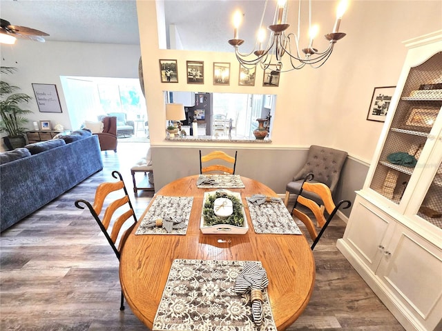 dining space featuring dark wood-type flooring, a textured ceiling, and ceiling fan with notable chandelier