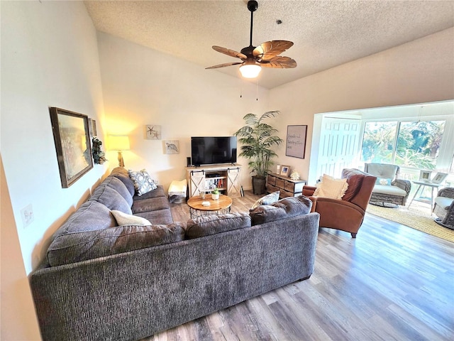 living room with a textured ceiling, wood-type flooring, and ceiling fan