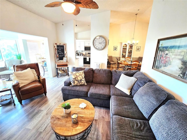 living room with high vaulted ceiling, light wood-type flooring, and ceiling fan with notable chandelier