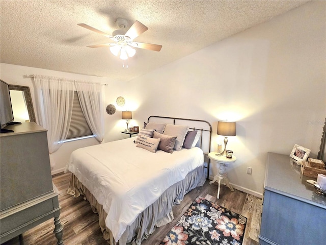 bedroom with dark wood-type flooring, a textured ceiling, and ceiling fan