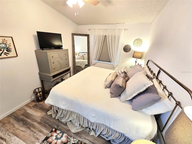 bedroom with a textured ceiling, ceiling fan, wood-type flooring, and vaulted ceiling