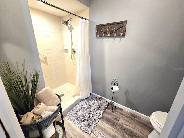 bathroom with toilet, a shower with shower curtain, and hardwood / wood-style floors