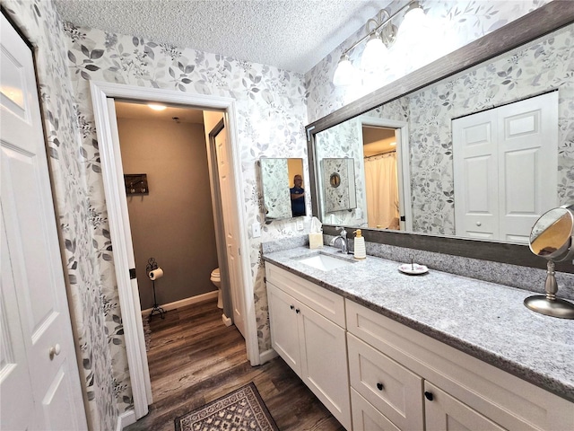 bathroom featuring vanity, a textured ceiling, hardwood / wood-style flooring, and toilet