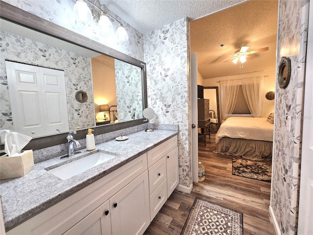 bathroom with vanity, hardwood / wood-style floors, a textured ceiling, and ceiling fan