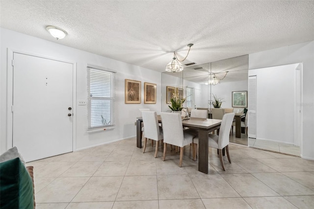 tiled dining room with a textured ceiling and a chandelier