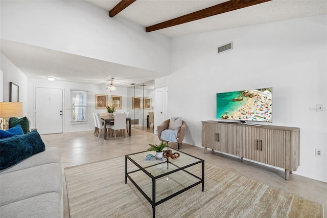 tiled living room with beam ceiling and a chandelier