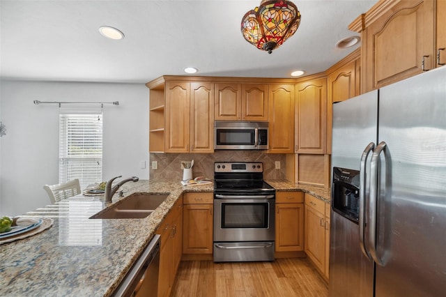 kitchen with tasteful backsplash, light stone countertops, light wood-type flooring, sink, and stainless steel appliances