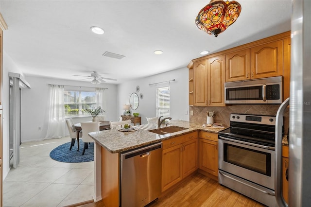 kitchen featuring appliances with stainless steel finishes, kitchen peninsula, sink, and a wealth of natural light