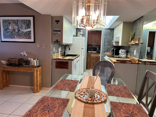 dining space featuring light tile patterned floors, a notable chandelier, a textured ceiling, and sink