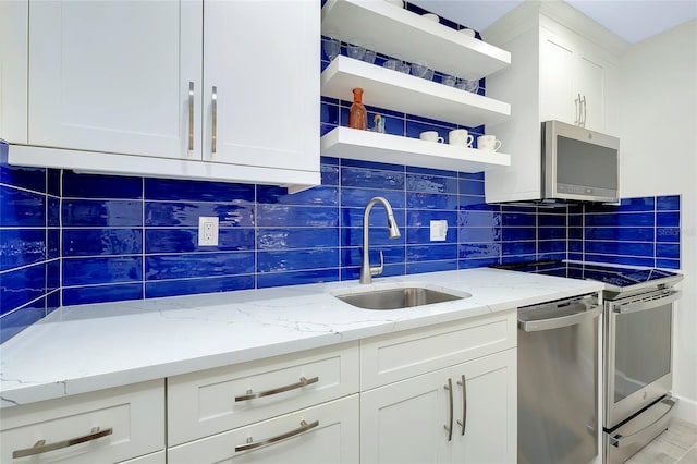 kitchen featuring white cabinets, tasteful backsplash, light stone counters, appliances with stainless steel finishes, and sink