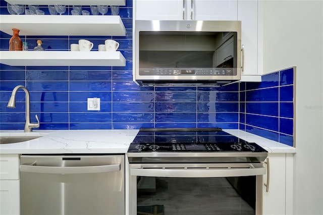 kitchen with tasteful backsplash, light stone countertops, sink, white cabinetry, and stainless steel appliances