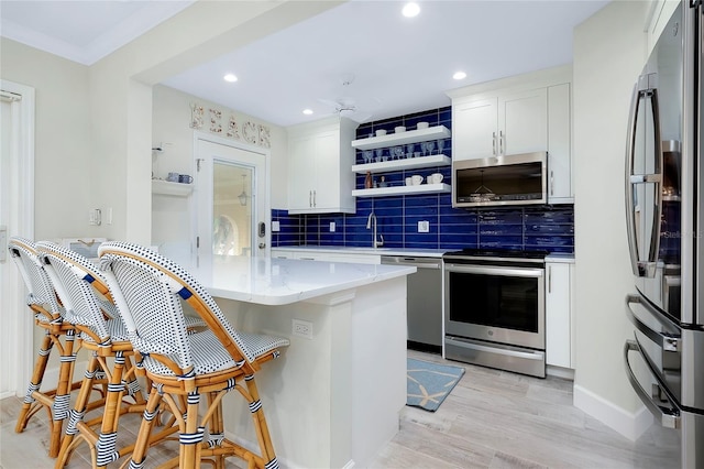 kitchen featuring white cabinetry, stainless steel appliances, light hardwood / wood-style flooring, and a kitchen bar