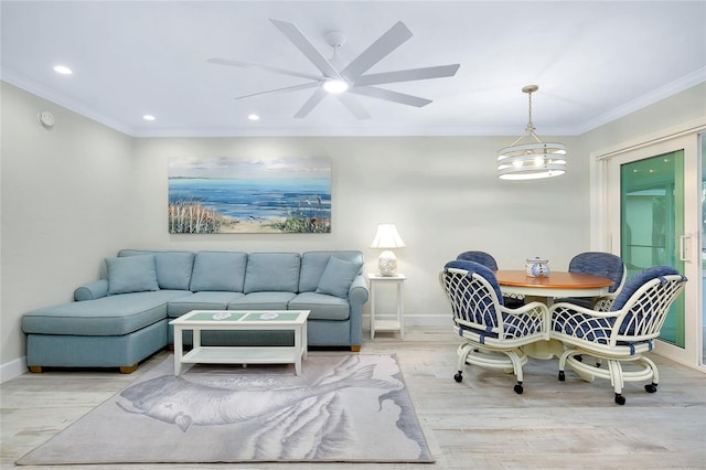 living room featuring crown molding, light wood-type flooring, and ceiling fan with notable chandelier