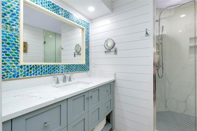 bathroom featuring a shower with door and vanity