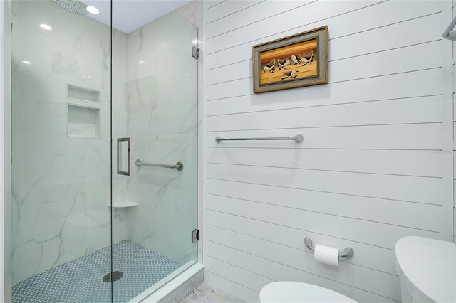 bathroom featuring a shower with door and toilet