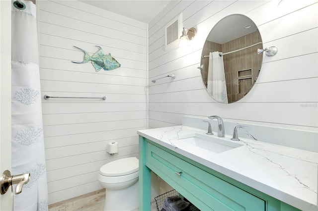 bathroom with wood walls, wood-type flooring, toilet, a shower with curtain, and vanity