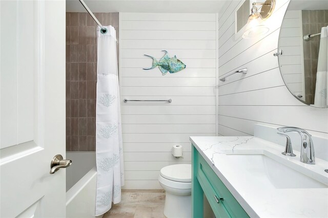 full bathroom with toilet, wooden walls, wood-type flooring, vanity, and shower / bathtub combination with curtain