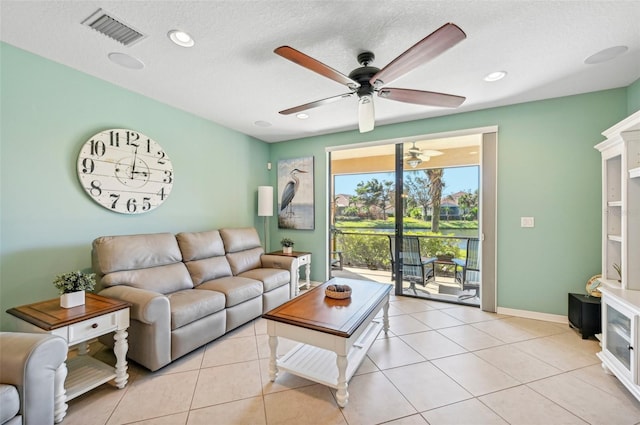 living room featuring a textured ceiling, light tile patterned floors, and ceiling fan