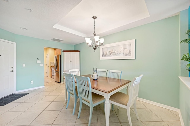 tiled dining area with a tray ceiling and a chandelier