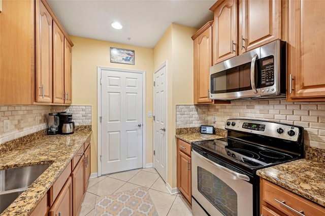 kitchen featuring light tile patterned floors, stone countertops, appliances with stainless steel finishes, and tasteful backsplash