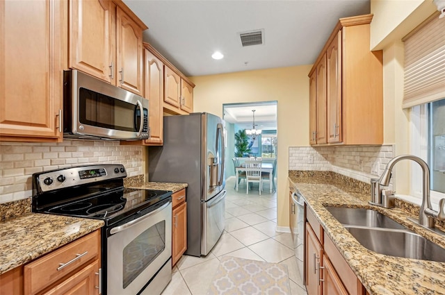 kitchen with sink, light tile patterned flooring, light stone counters, and stainless steel appliances