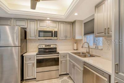 kitchen featuring appliances with stainless steel finishes, sink, gray cabinets, and a raised ceiling