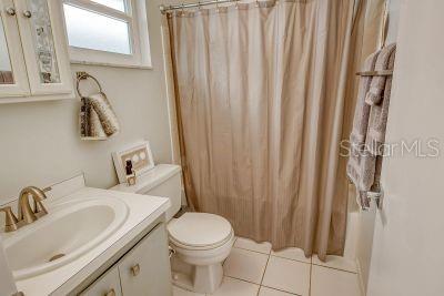 bathroom with vanity, curtained shower, toilet, and tile patterned flooring