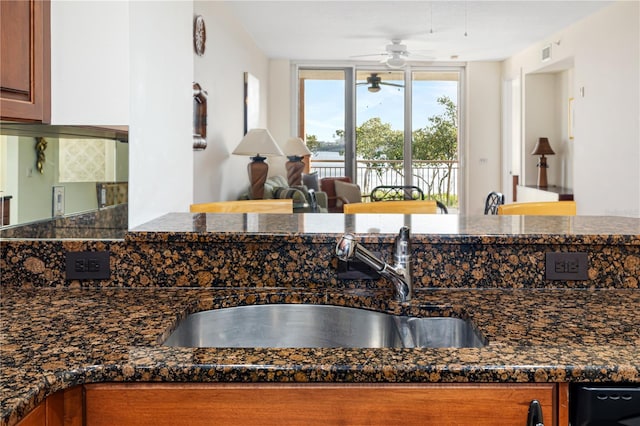 kitchen with dark stone countertops, ceiling fan, and sink