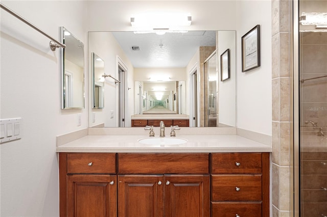 bathroom featuring vanity, walk in shower, and a textured ceiling