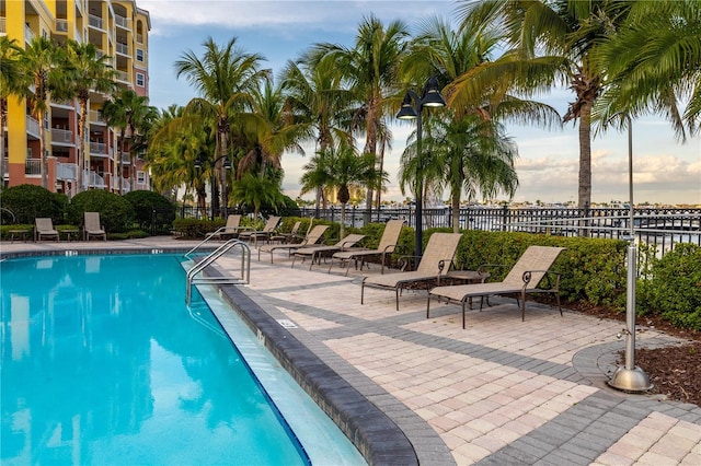 pool at dusk featuring a patio