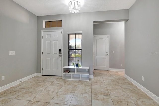 tiled entryway featuring a notable chandelier and a textured ceiling