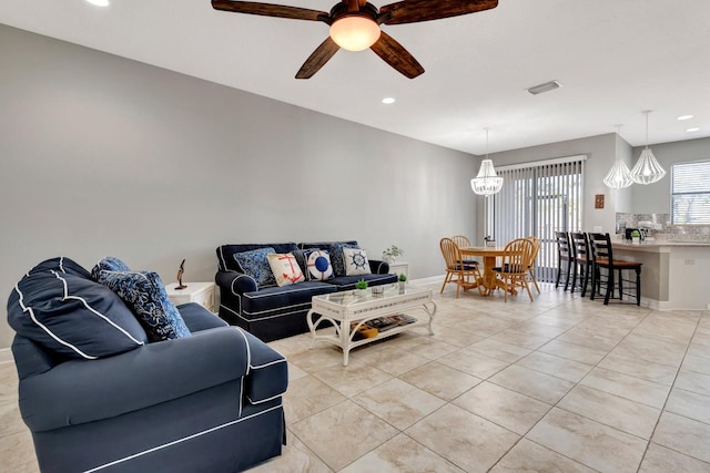 living room with ceiling fan with notable chandelier and light tile patterned floors