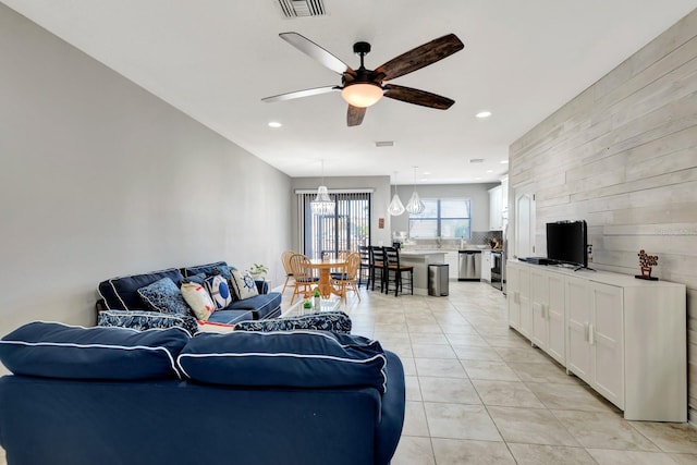 living room with ceiling fan, wood walls, and light tile patterned floors