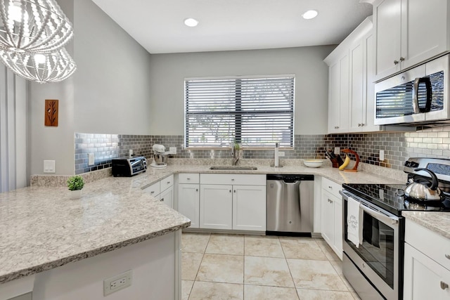 kitchen featuring stainless steel appliances, sink, pendant lighting, and white cabinets